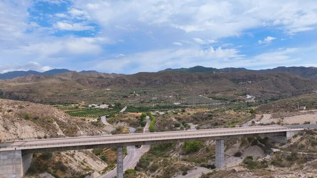 Aerial glides over a rail bridge for the unfinished Almeria to Madrid AVE rail line amongst olive groves, dry river gullies, and arid hillsides. Tabernas Almeria province Espana Spain