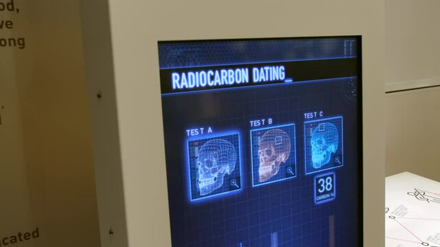 A digital display screen in a forensics crime lab showing a radiocarbon dating process with three skull for scientific research and archaeology