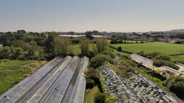 Flight over derelict glasshouses flying low on bright sunny day showing dilapidation