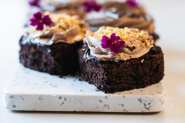 Chocolate sponge cakes with whipped cream and flower decorations served on cutting board on table in bakery