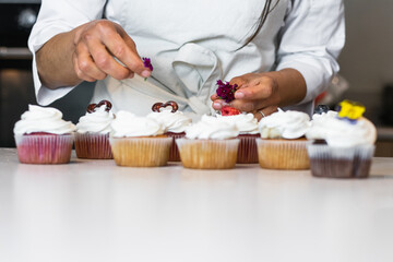 Pastry chef hands working on sweet muffins with cream