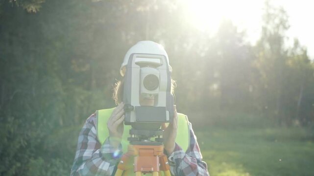 Engineer Topographer woman performs engineering survey and topography work on a sunny day, geodetic work, topography, land surveying, cadastral work.