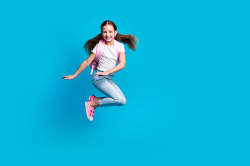 Photo of cute attractive little lady dressed white t-shirt backpack jumping high empty space isolated blue color background