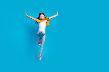 Photo of cheerful pretty little lady dressed tied jumper jumping high flying empty space isolated blue color background