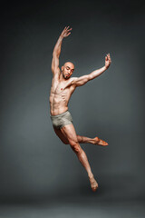 Muscular man dancer leaping gracefully in studio