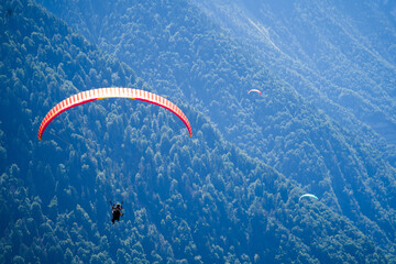 paraglider in the air with a colorful parachute in monochrome background of a hazy mountain