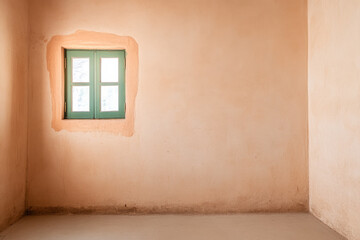 A simple room with warm earth-toned walls and a green window letting in natural light