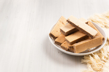 Chocolate flavored wafers on a white plate with a cup of tea in the background. with copy space. perfect for recipe, article, catalogue, or any commercial purposes.