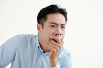 Asian man sitting with pensive expression on white background