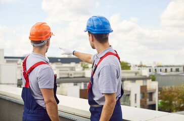 Builders and workers stand on a roof planning the construction of a building site. Engineers and technicians prepare for the project, ensuring efficient and safe construction processes.