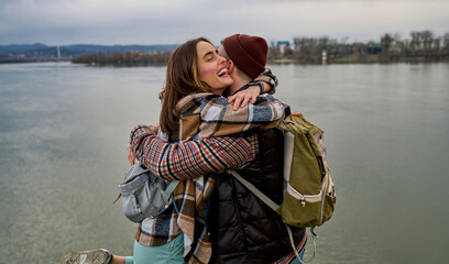 Joyful couple sharing a playful moment on a scenic riverbank, basking in their love.