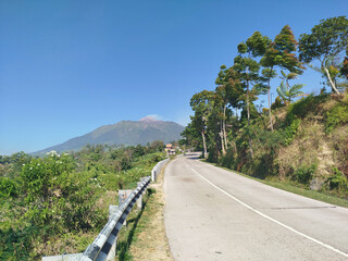 road with mountain background. rural road in mountain area with many trees which is cool and fresh