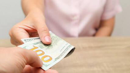 Cash turnover. Man gives banknotes to woman. Dollars. Close-up of hands with cash. Payment In Cash