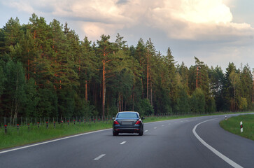 The car drives along the highway in the evening in summer