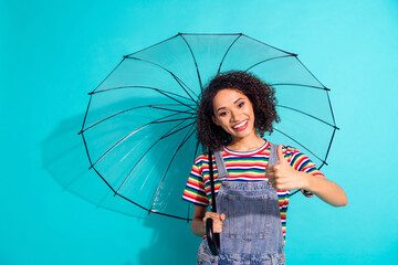 Photo of positive girl hold umbrella make thumb up sign isolated cyan color background
