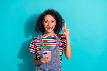 Photo of amazed girl hold cell smart device have idea point finger isolated cyan color background