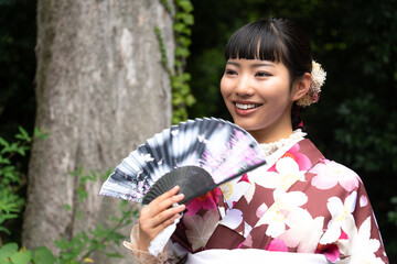 扇子を持ちポーズをとる着物の女性