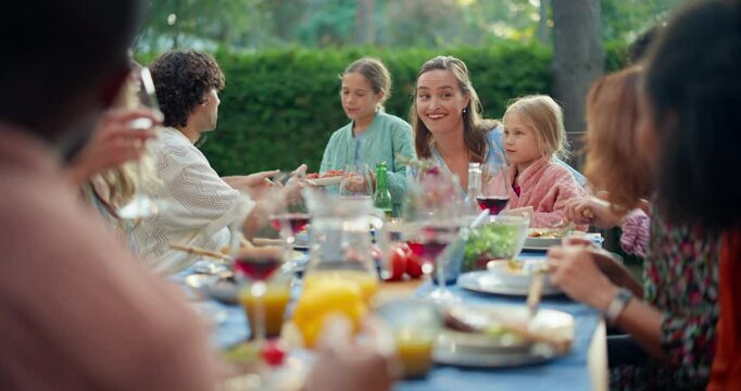 Parents, Children and Friends Gathered at a Barbecue Dinner Table in a Home Backyard. Young People Have Fun Conversations, Eat and Drink. Garden Party Celebration in a Garden