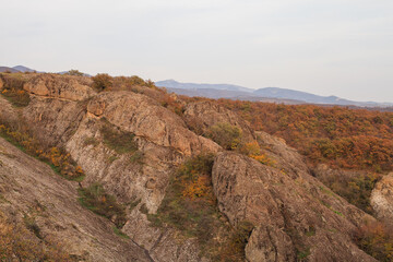 a panoramic view of autumn landscape with mountain hills surrounded by trees with yellow and red foliage at birtvisi canyon in georgia at a sunset light