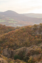 a panoramic view of autumn landscape with mountain hills surrounded by trees with yellow and red foliage at birtvisi canyon in georgia at a sunset light