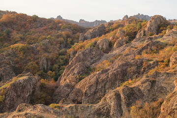 a panoramic view of autumn landscape with mountain hills surrounded by trees with yellow and red foliage at birtvisi canyon in georgia at a sunset light
