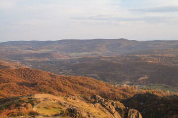 a panoramic view of autumn landscape with mountain hills surrounded by trees with yellow and red foliage at birtvisi canyon in georgia at a sunset light