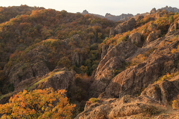a panoramic view of autumn landscape with mountain hills surrounded by trees with yellow and red foliage at birtvisi canyon in georgia at a sunset light