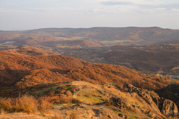 a panoramic view of autumn landscape with mountain hills surrounded by trees with yellow and red foliage at birtvisi canyon in georgia at a sunset light