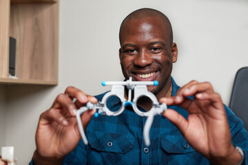 Smiling Optometrist Holds Eye Testing Equipment in Professional Office Setting