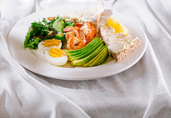 Delicious healthy breakfast plate with shrimps avocado and eggs for keto diet