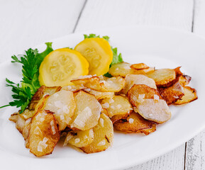 Delicious roasted potatoes with greens and zucchini slices on white plate