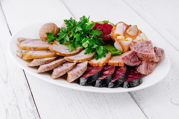 White plate presenting variety of delicious meat products on wooden table