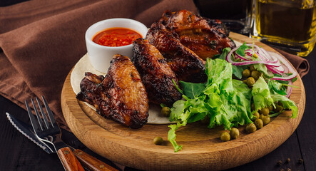 Grilled chicken wings served with salad on wooden board