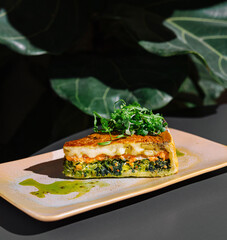 Delicious slice of quiche with salmon and spinach resting on plate