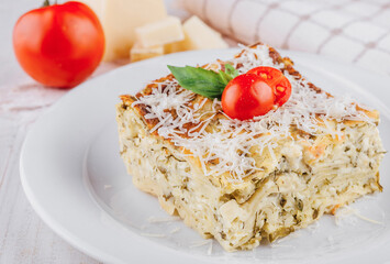 Slice of vegetarian lasagna garnished with fresh ingredients on white plate