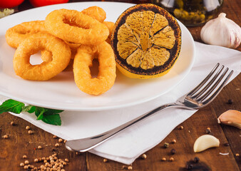 Delicious fried calamari rings with lemon on a plate