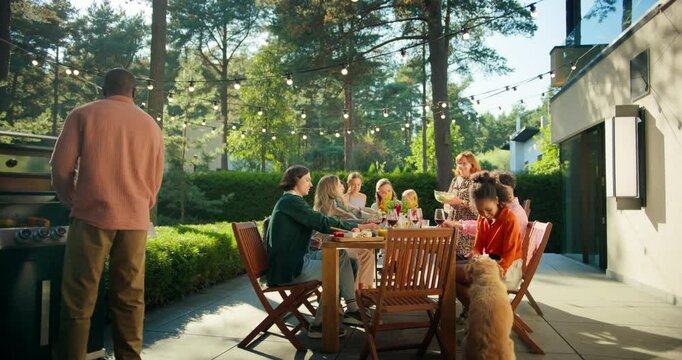 Diverse Men and Women Enjoy a Lively Garden Party, Sharing Food and Drinks Outdoors. Man Grilling Meat Nearby while a Golden Retriever Roams Around, Adding to the Festive Atmosphere. Slow Motion