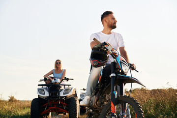Fototapeta premium Get ready for the ride. Man on motorcycle and woman is on the ATV, outdoors together