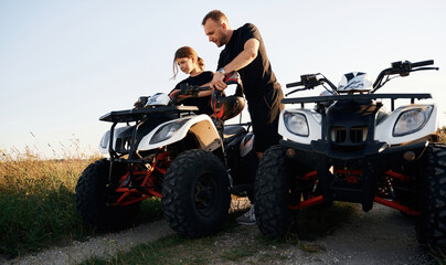 Fototapeta premium Showing how the machine works. Father and daughter are with ATV outdoors