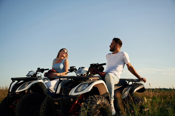Sitting, taking a break. Man and woman are on ATV outdoors