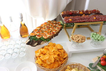 Buffet table with potato chips, nuts and sandwiches.