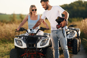 In sunglasses, taking a break. Man and woman are on ATV outdoors