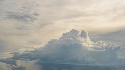  Dramatic cloudscape featuring towering, fluffy clouds against a soft, pastel sky. The scene...