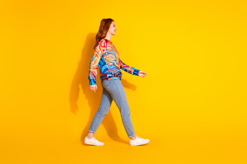 Full length photo of nice cheerful girl wear trendy print clothes look empty space isolated on vivid yellow color background