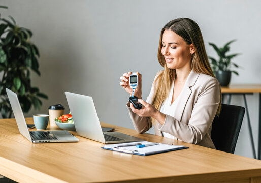 Businesswoman checking blood sugar level in modern office setting for diabetes management