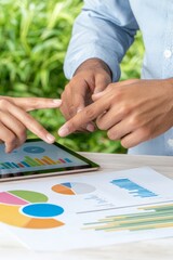 Obraz premium Two professionals collaborate over charts and data on a tablet, showcasing productivity and teamwork in a green workspace.