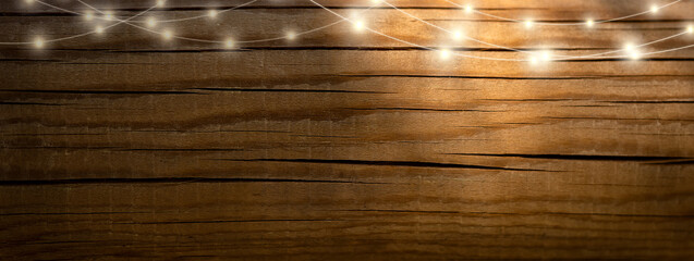 Christmas panoramic background with copy space. Top view of an empty rustic wooden table with string lights © ELuki