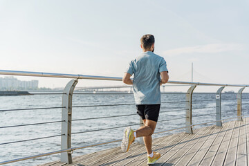 Man Jogging Along a Waterfront Promenade on a Sunny Day With a City Skyline in the Background