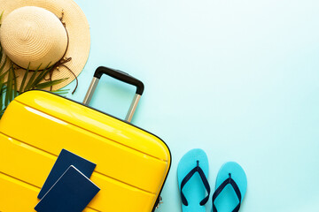 Suitcase, hat and flip flops on blue background. Happy Holidays, travel concept. Flat lay with space for text. © nadianb