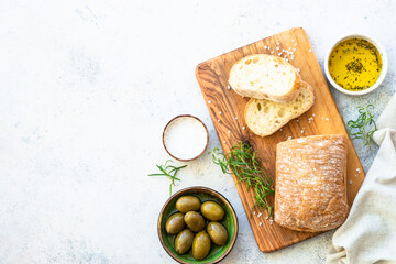 Ciabatta bread on wooden board with olive oil. Top view on white table with copy space.